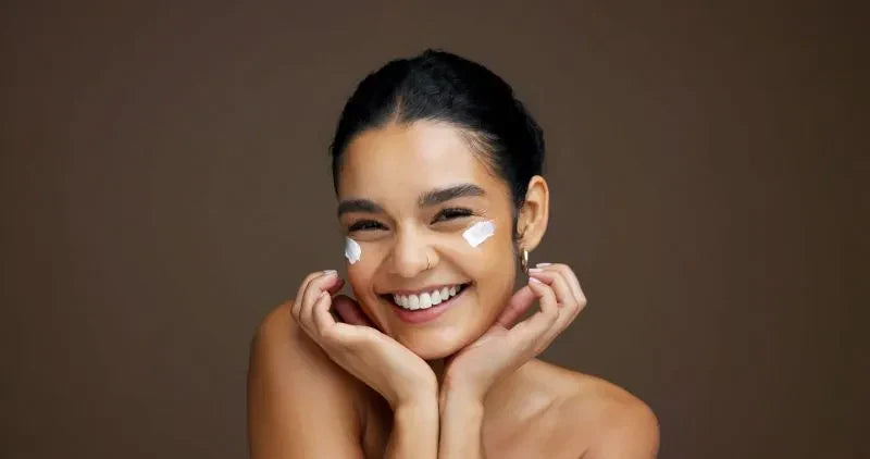 A woman applying skincare cream to her face, emphasizing the importance of hydration and skin hydration supplements for maintaining healthy, moisturized skin.