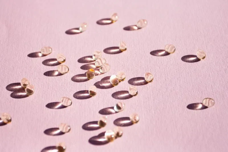 Probiotic supplements scattered on a pink surface, showcasing capsules designed for gut health.